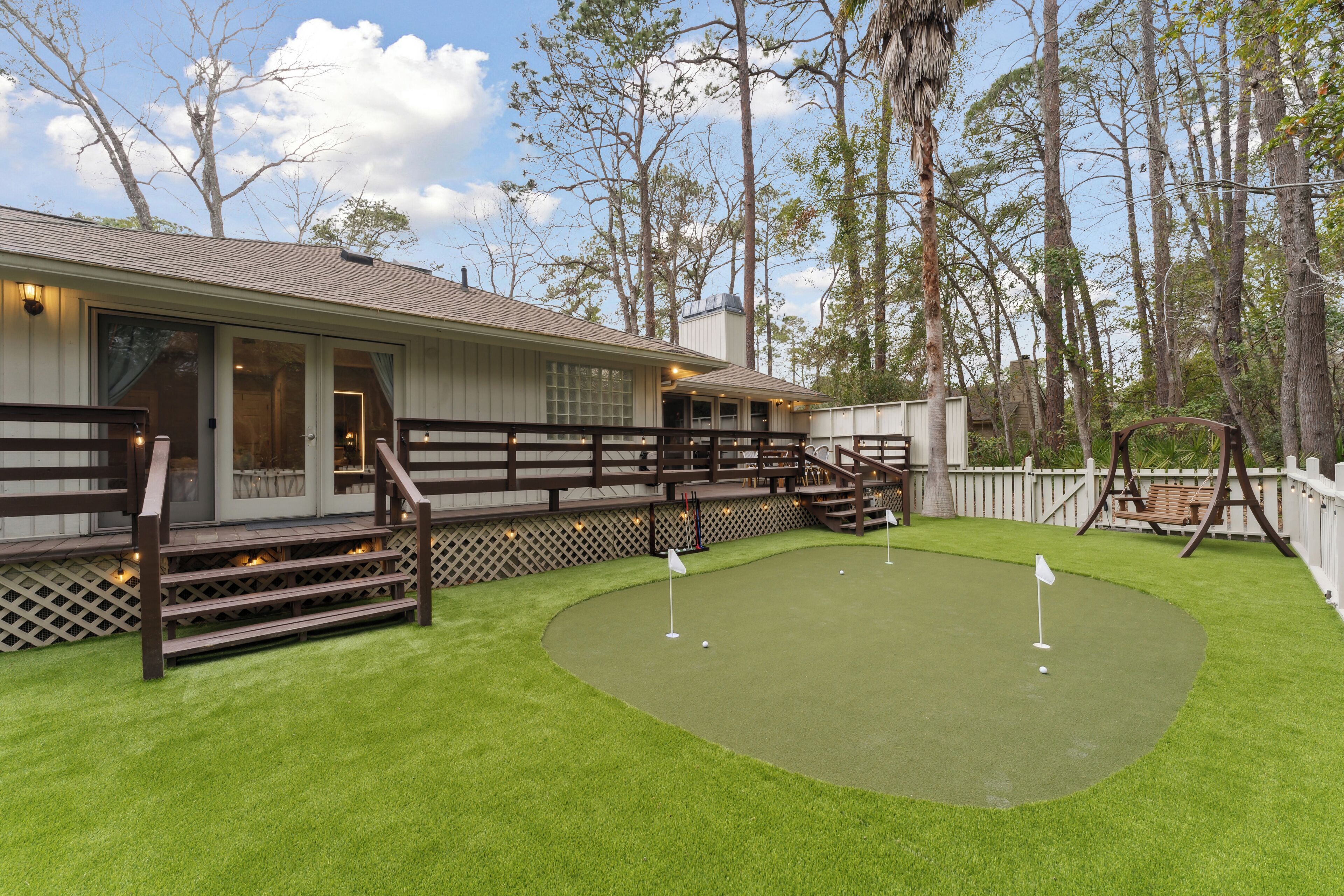 Et hus med terrasse, lille patio og putting green.