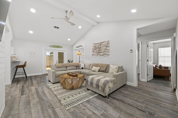 A modern living room with a sectional sofa, a wooden coffee table, and a ceiling fan. - Beach Haven 3BR 2bath (Panama City Beach)