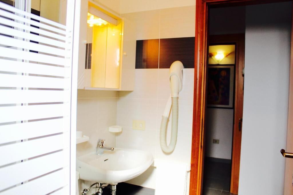 Un baño con un lavamanos blanco, un espejo y un teléfono.
