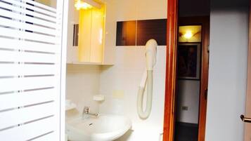 Un baño con un lavamanos blanco, un espejo y un teléfono.