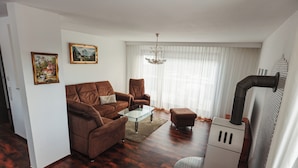 A living room with a brown sofa, a glass coffee table, a white cabinet, and a fireplace. - Hexenlandhaus Tom, mit Sauna & 2 Öfen (Braunlage)