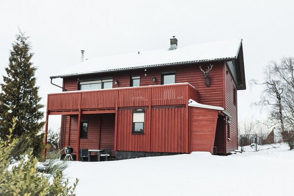 Ett rött trähus med en balkong och en skorsten.
