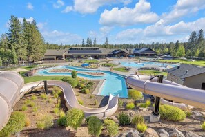Un resort con diverse piscine, uno scivolo acquatico e un edificio ampio dal design moderno.