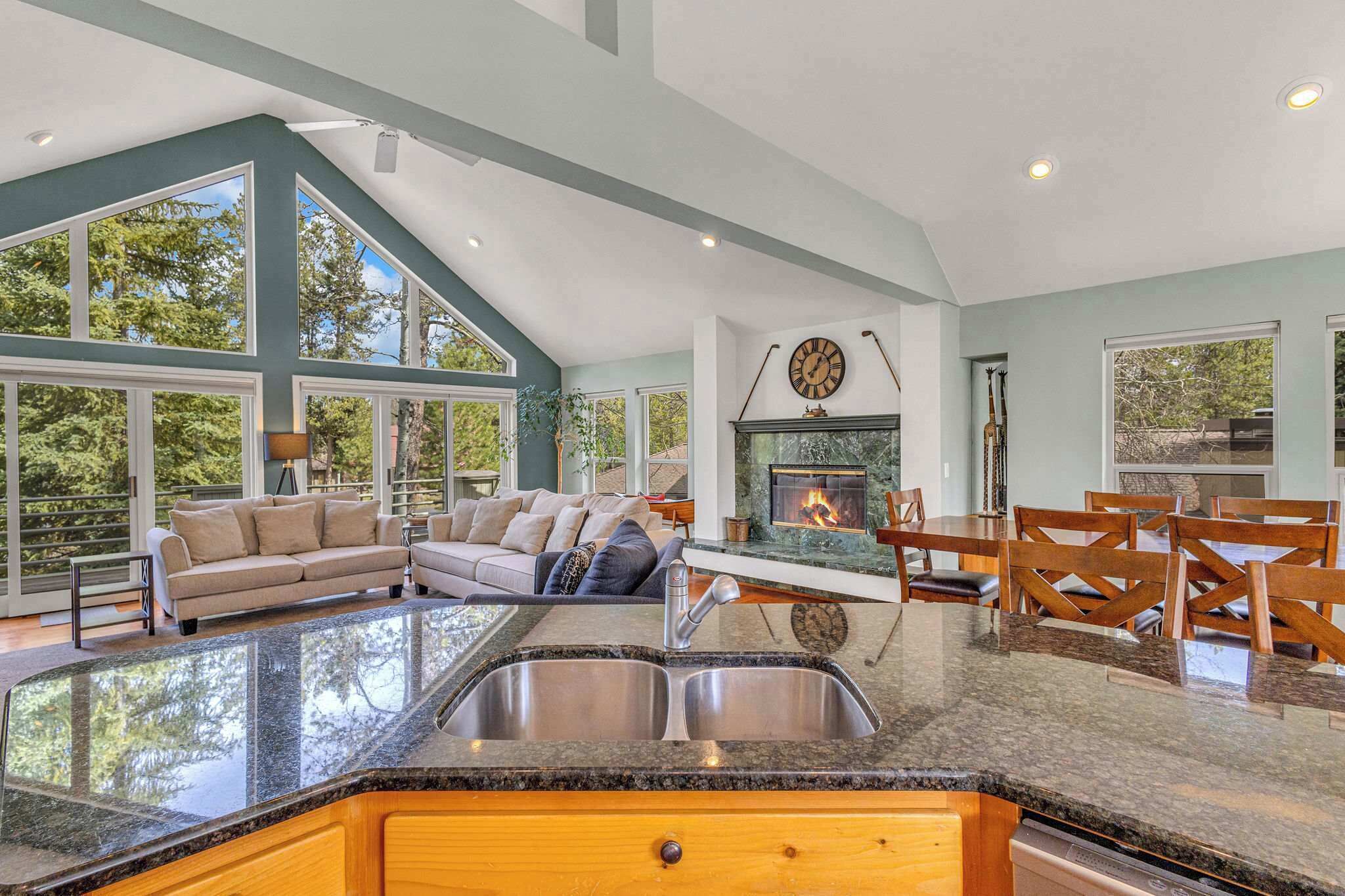 A spacious living area with a large window, a fireplace, and a dining table with chairs.