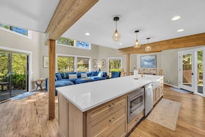 A spacious kitchen with a large island, wooden beams, and a view of the outdoors.