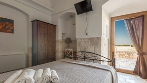 Une chambre à coucher avec un lit, des serviettes pliées, une armoire en bois, une télévision et une vue sur l’extérieur.