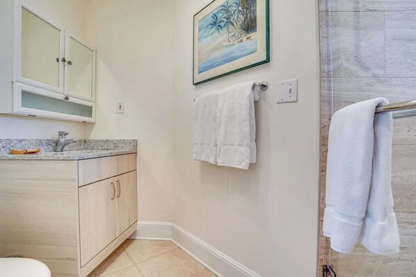 A bathroom with a sink, cabinets, a towel rack, and a painting on the wall.