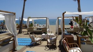 A beachside lounge area with outdoor seating and umbrellas, overlooking the sea. - Acogedor Apartamento de un Dormitorio en un Entorno Tranquilo (Calahonda)