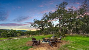 An outdoor seating area with Adirondack chairs and a fire pit surrounded by trees. - Casa Robles- Mockingbird I Couples, stargazing (Wimberley)