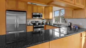 A modern kitchen with wooden cabinets, stainless steel appliances, and a granite countertop. - Casa Robles- Mockingbird I Couples, stargazing (Wimberley)