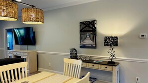 A dining area with a table, chairs, a television, and wall art.