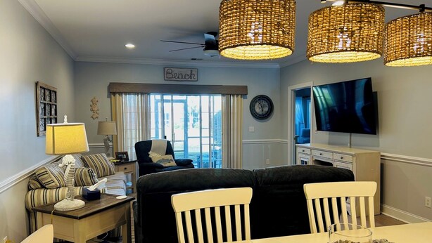 A living room with a sofa, chairs, a dining table, and a TV.