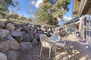 Un patio con muro de piedra, mobiliario exterior y vista a una montaña.