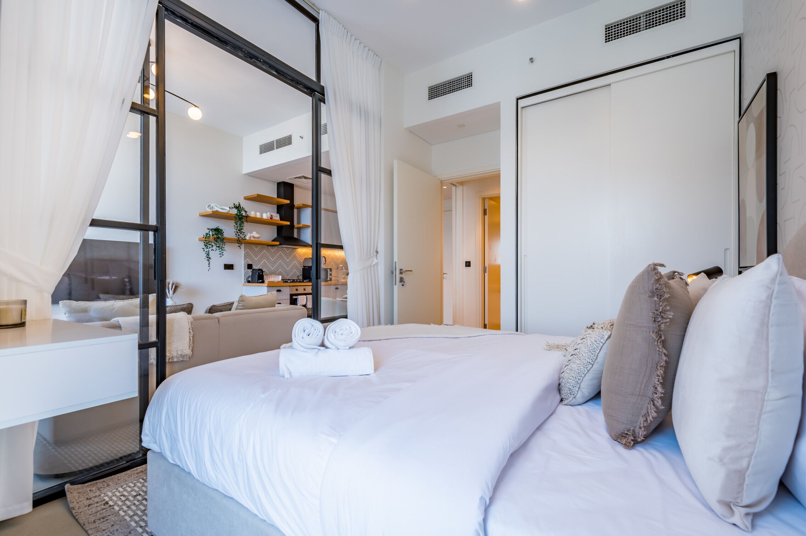 Ein modernes Hotelzimmer mit einem großen Bett, einem Schreibtisch und Blick zur Küche.