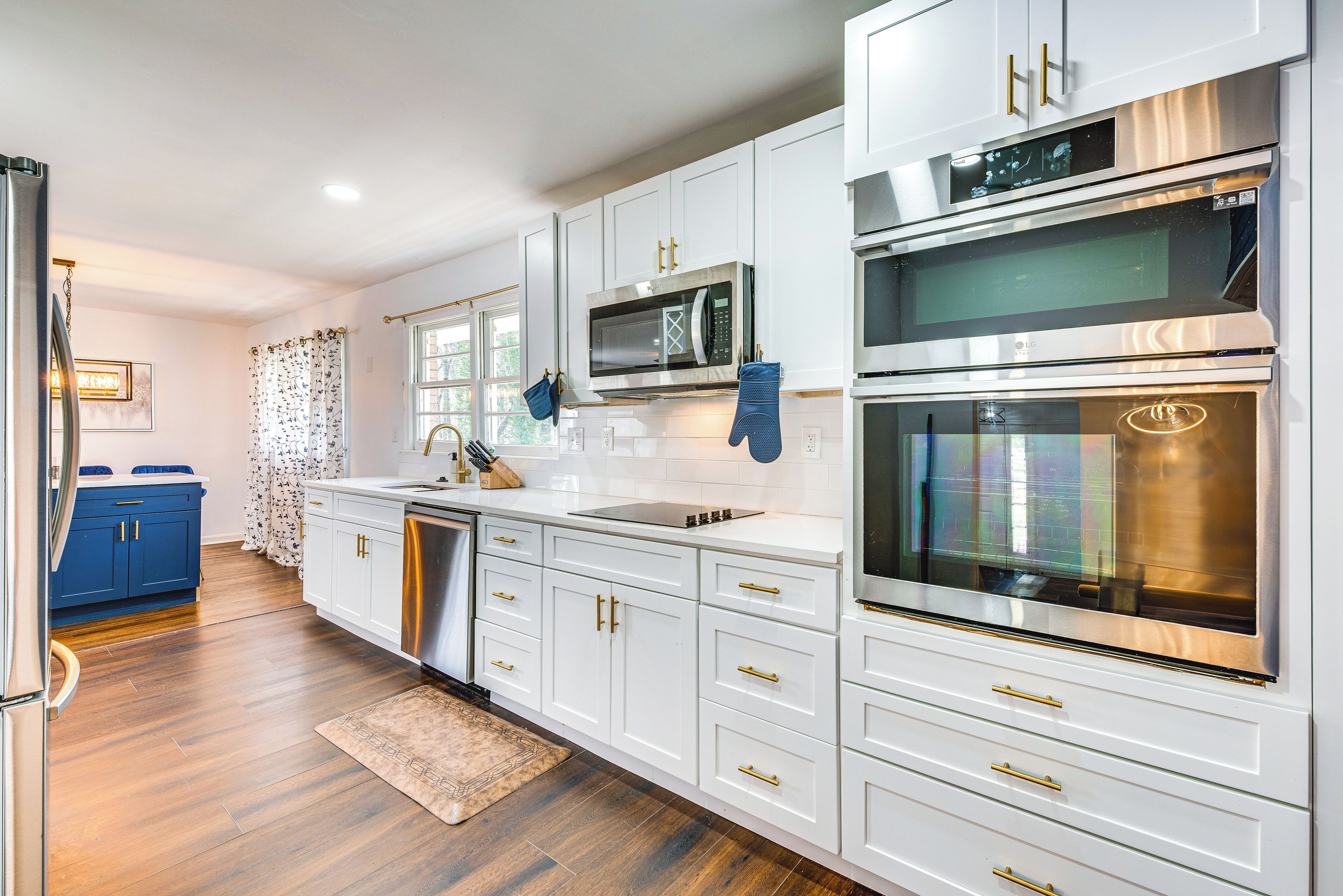 Una cocina moderna con armarios blancos, electrodomésticos de acero inoxidable y piso de madera.