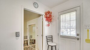 A hallway with a white door, a clock, a chair, and a patterned rug. - Charming Orem Home w/ Yard - Near BYU & Uvu! (Orem)