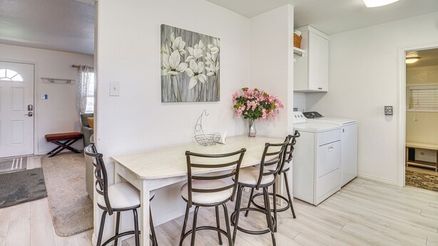 A dining area with a table, chairs, a vase of flowers, and a painting on the wall. - Charming Orem Home w/ Yard - Near BYU & Uvu! (Orem)