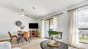 A spacious living room with a dining area, a large window with curtains, a ceiling fan, and a flat-screen TV. - 5 Mi to Strip! Pointe Royale Condo w/ Indoor Pool (Branson)
