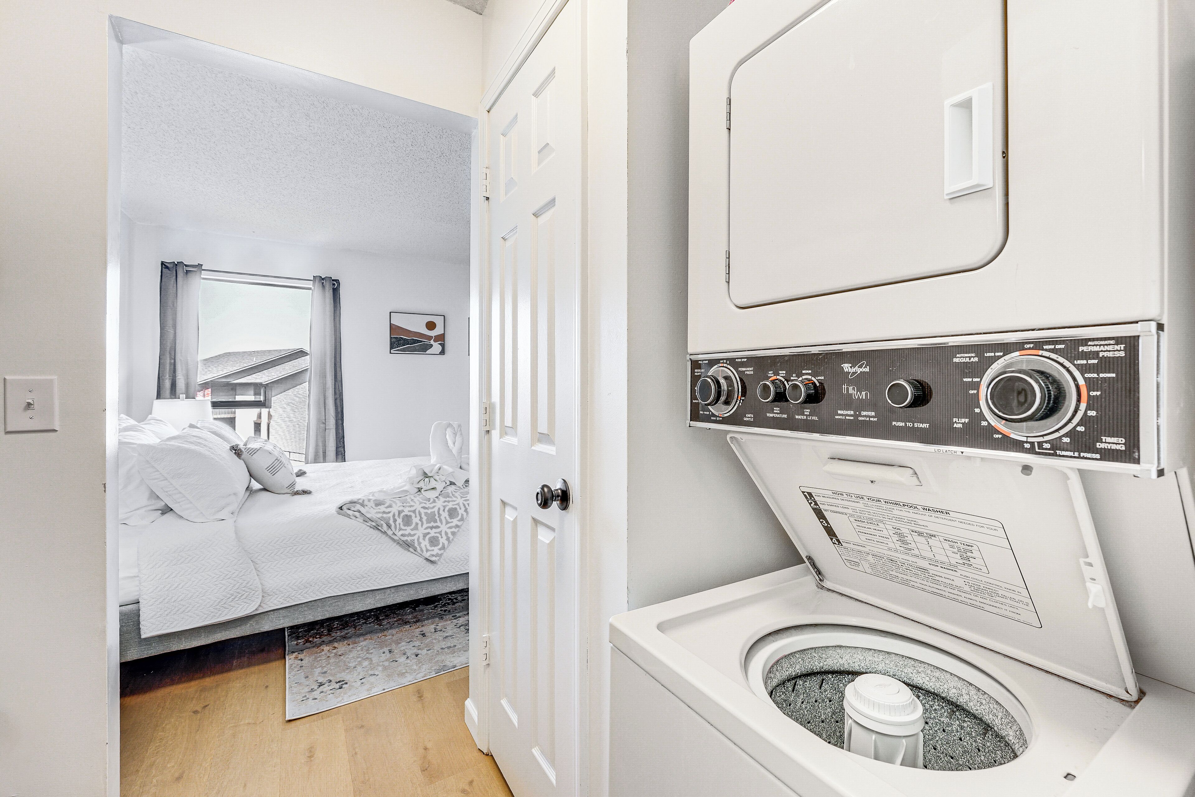 A bedroom with a bed, a door, and a washing machine.