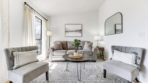 A living room with a sofa, two armchairs, a coffee table with a plant, and a large window with curtains. - 5 Mi to Strip! Pointe Royale Condo w/ Indoor Pool (Branson)