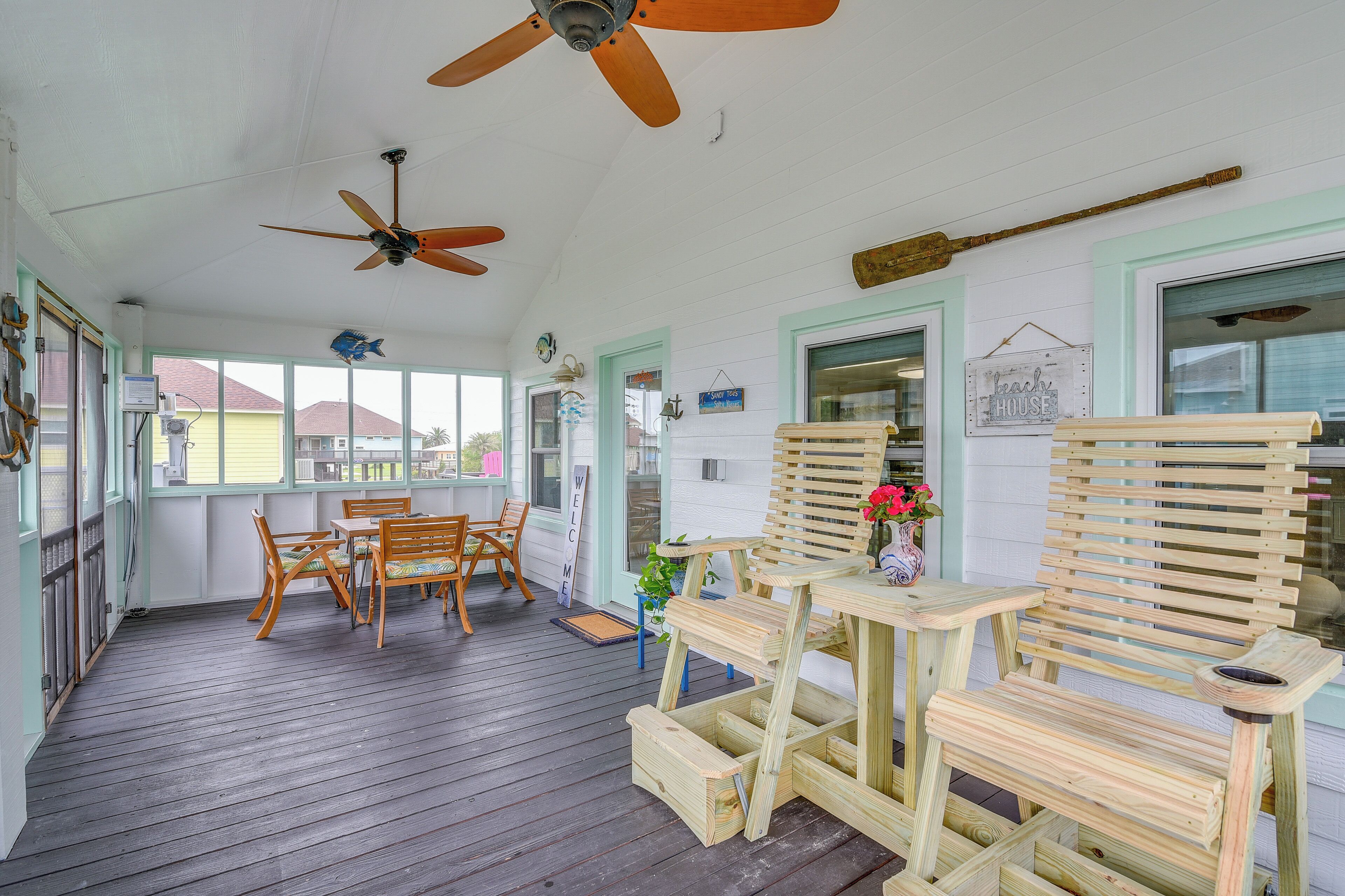 Eine überdachte Veranda mit Holzmöbeln, Deckenventilatoren und Blick ins Freie.