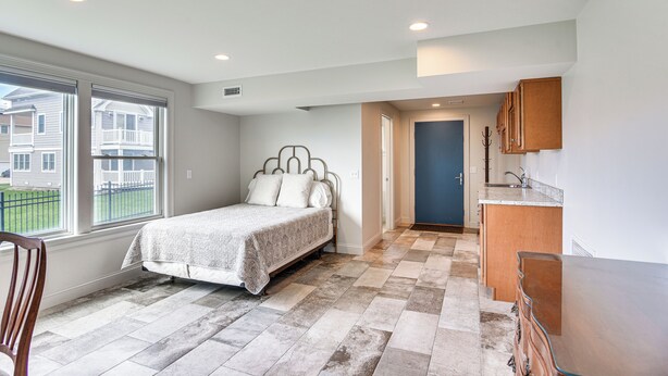 Un dormitorio con cama, una silla, una zona de cocina y vistas al exterior.