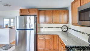 Una cocina moderna con armarios de madera, un refrigerador de acero inoxidable, un reloj y un microondas.