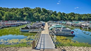 A marina with boats docked, a dock leading to the water, and a forested hillside in the background. - Galena Townhome w/ Deck & Golf Course View! (Galena)