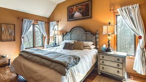 A bedroom with a large bed, a wooden headboard, a nightstand with a lamp, and a window with curtains. - Galena Townhome w/ Deck & Golf Course View! (Galena)