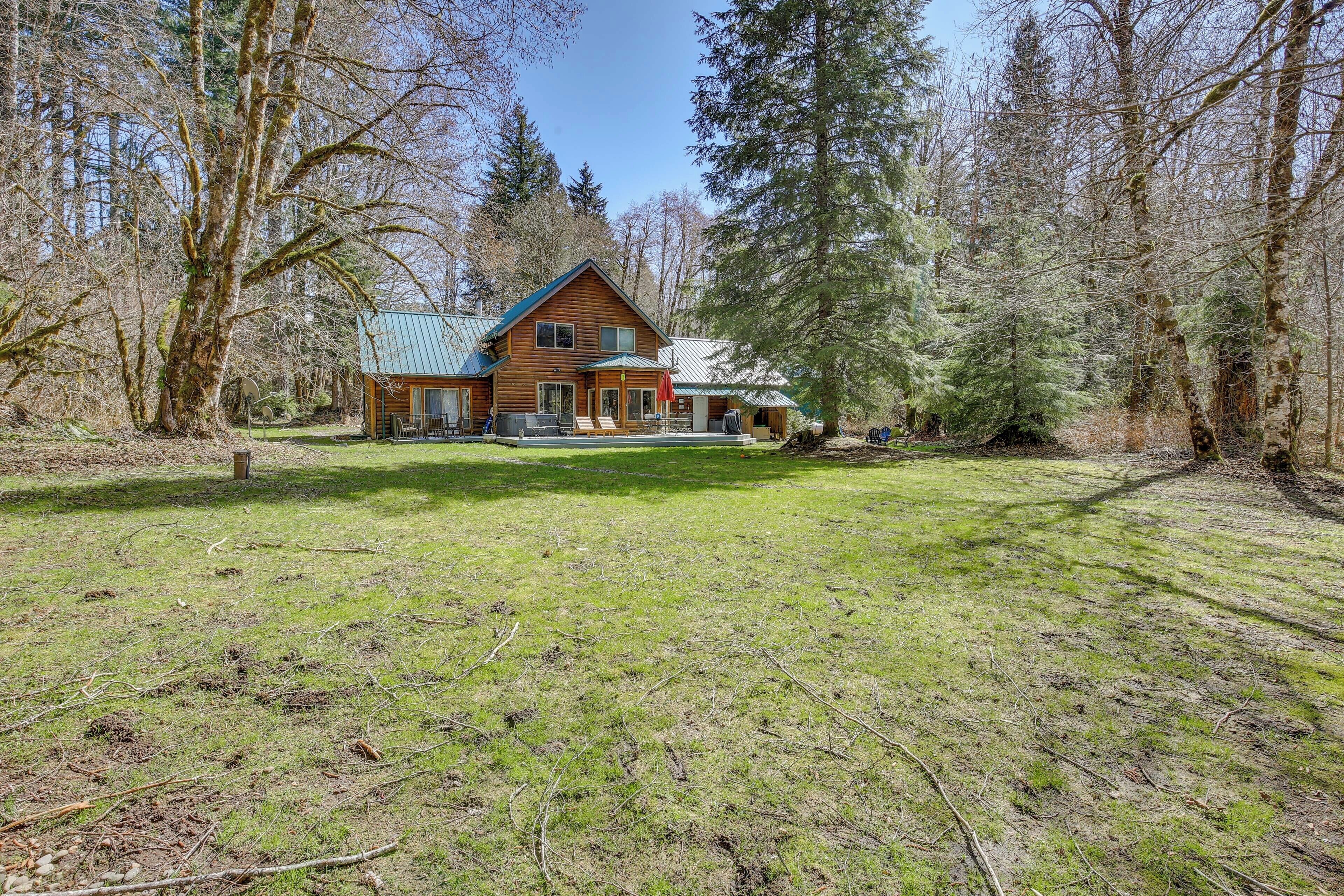 A log cabin with a metal roof, surrounded by a forest.