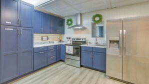 A kitchen with blue cabinets, stainless steel appliances, and a light-colored floor.