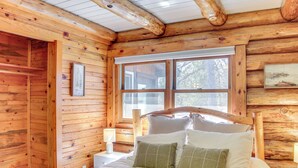 A wooden cabin bedroom with a bed, pillows, a window, and a nightstand. - Lakefront Park Rapids Cabin w/ Decks & Boat Dock! (Park Rapids)