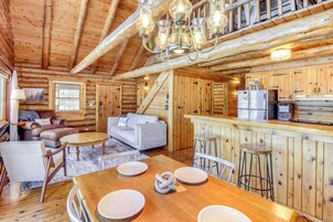 Interior de una cabaña de troncos con comedor, cocina y sala de estar.