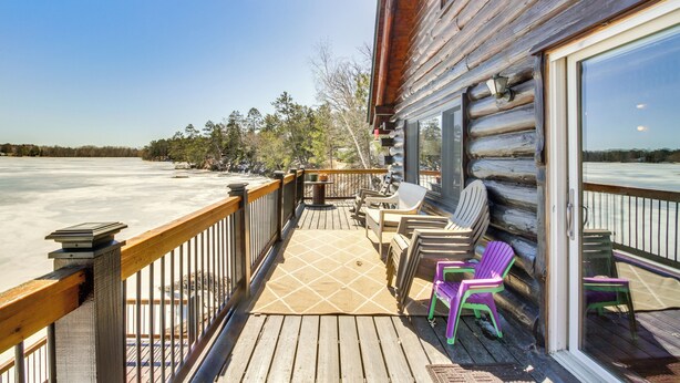 A wooden deck with outdoor furniture, a glass door leading to a room, and a view of a frozen lake. - Lakefront Park Rapids Cabin w/ Decks & Boat Dock! (Park Rapids)