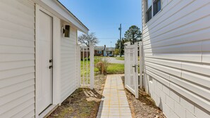 A narrow pathway between two white mobile homes with a small garden area visible in the background. - White Sail on the Potomac - Coastal Modern (Colonial Beach)
