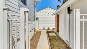 A narrow pathway leading to a white building with a sloped roof. - White Sail on the Potomac - Coastal Modern (Colonial Beach)