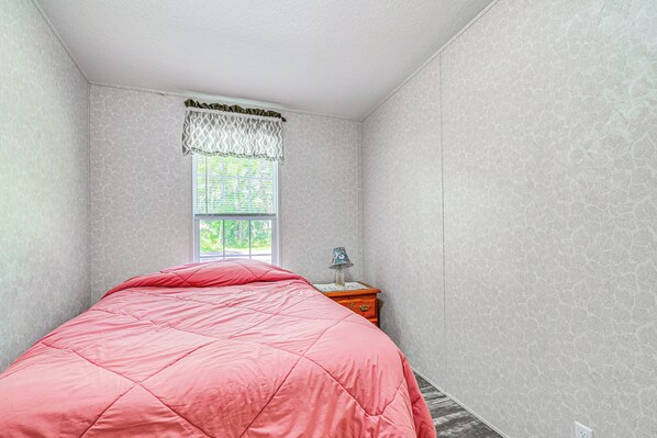A bedroom with a bed, a window with a patterned valance, a nightstand with a lamp, and a dresser. - 7 Mi to Crystal River: Home w/ Yard & Fire Pit! (Citrus Springs)