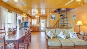 A cozy cabin interior with a dining area, sofa, and staircase. - Lakefront Delta Cabin Rental w/ Boat Dock + Deck! (Delta)