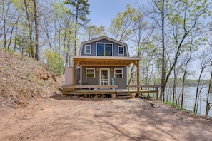 A cabin with a wooden deck, a front porch, and a view of the lake. - Lakefront Delta Cabin Rental w/ Boat Dock + Deck! (Delta)