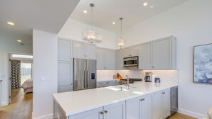 A modern kitchen with white cabinetry, stainless steel appliances, and pendant lighting. - Sleek Oxnard Townhouse w/ Balconies: Walk to Beach (Oxnard)