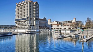 A high-rise hotel with multiple balconies, a marina with boats, and a clear blue sky.