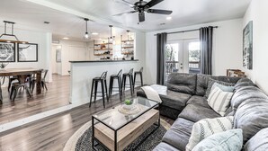 Ein modernes Wohnzimmer mit einem Glastisch, einem Ledersofa und einem Essbereich mit Holztisch und Stühlen.