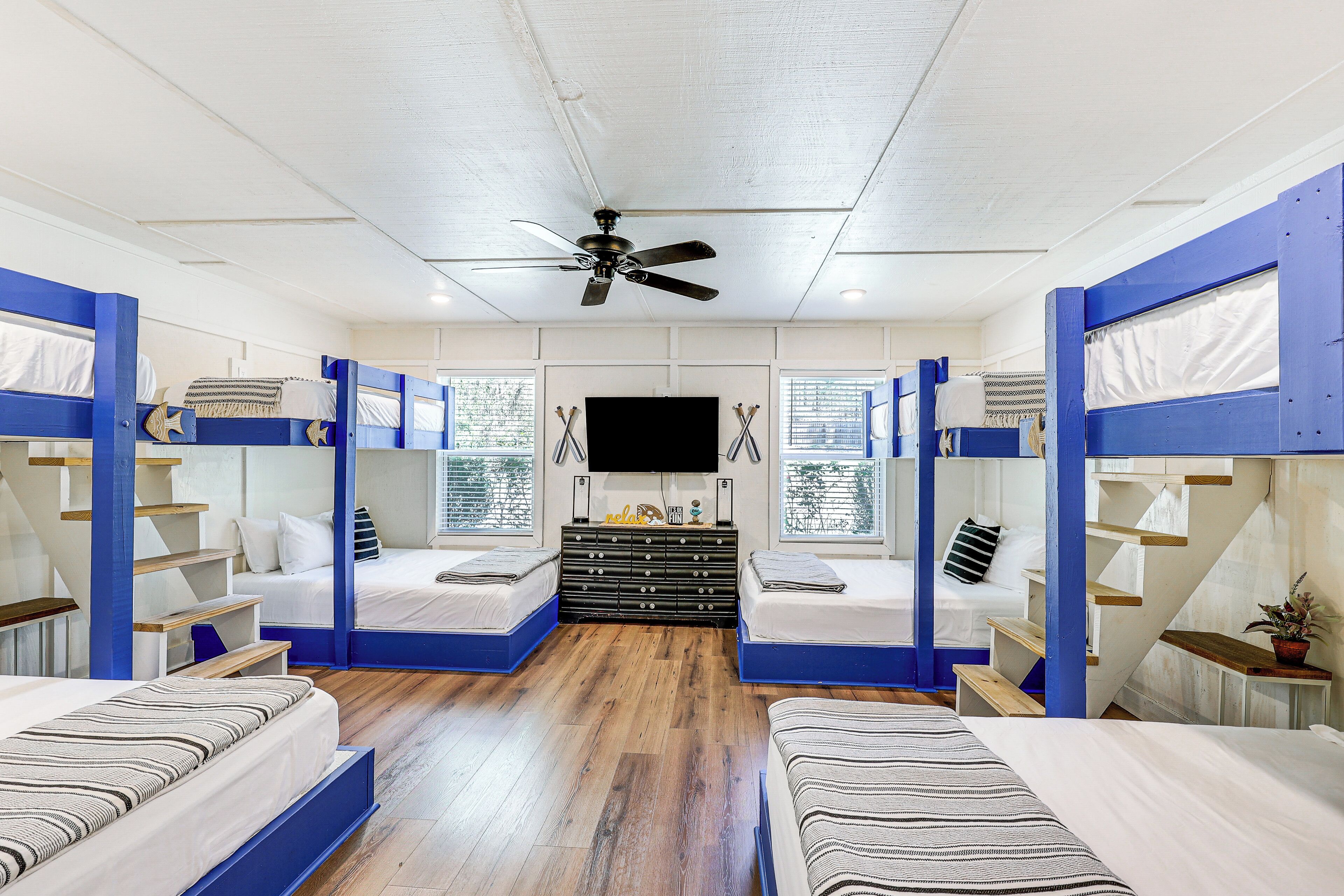 A room with bunk beds, a flat-screen TV, and a ceiling fan.