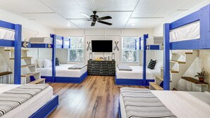 Ein Zimmer mit Etagenbetten, einem Flachbildfernseher und einem Deckenventilator.