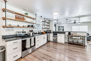 A modern kitchen with wooden shelves, a stove, and a coffee station. - Riverfront Royal Home w/ Hot Tub & Fire Pits! (Royal)