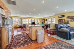 A spacious kitchen with wooden cabinets, a central island, and a dining area with chairs. - Waterfront Forest Lake Studio w/ Shared Dock! (Forest Lake)
