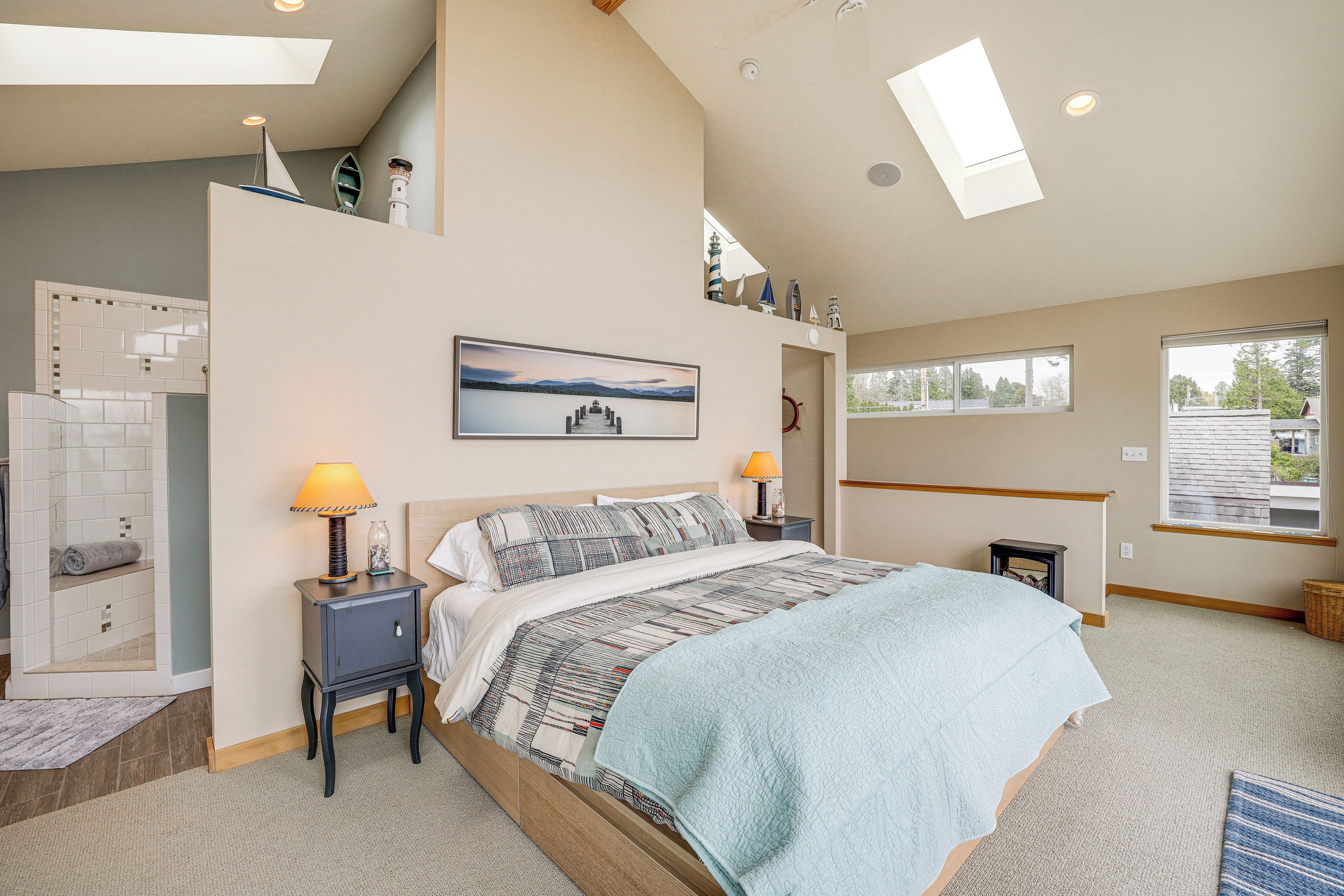 A bedroom with a large bed, two bedside tables, a nightstand, a window, and a skylight.