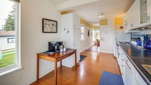 Una cocina moderna con suelo de madera, armarios blancos y una zona de comedor con mesa y sillas.