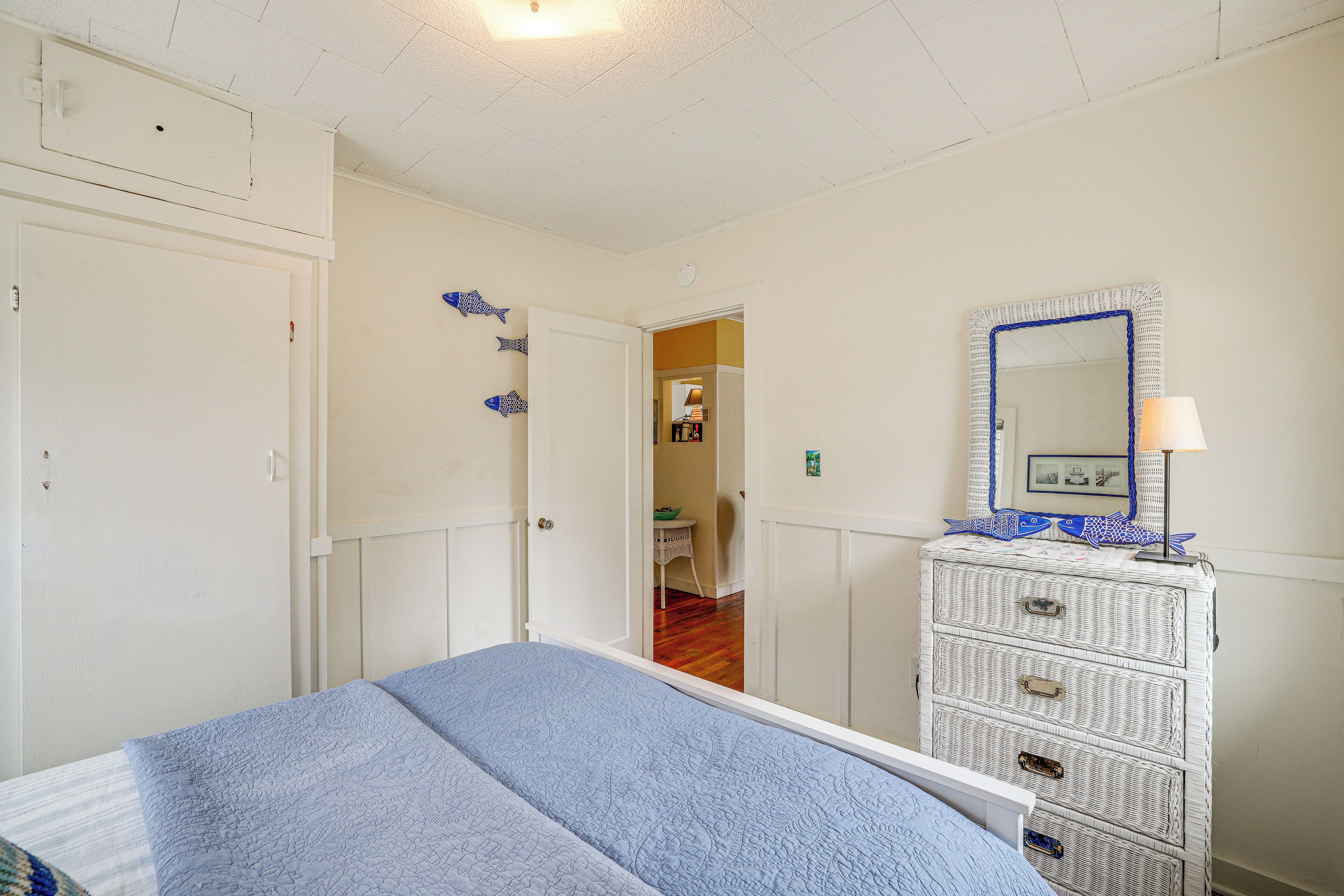 A bedroom with a bed, a dresser, and a door leading to another room.