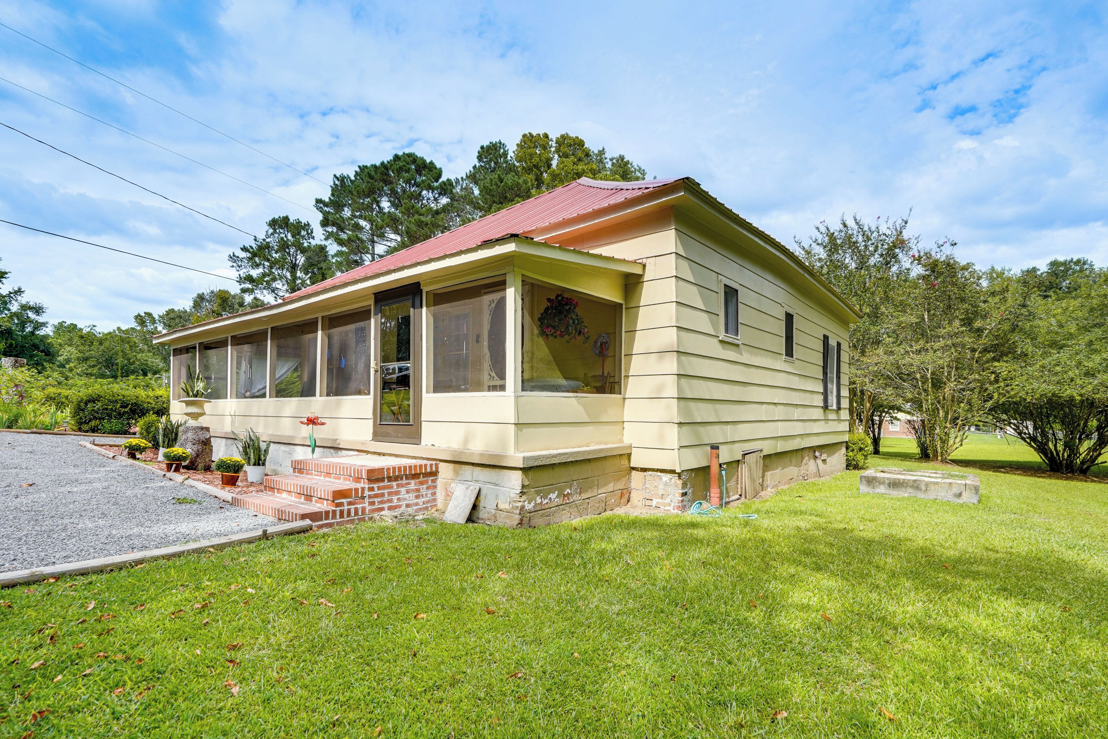 A single-story house with a red roof, a front porch, and a small front yard.